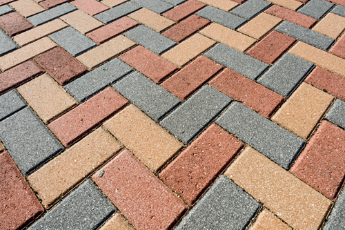 Rubber pavers installed in such a way to closely resemble bricks. The pavers are black, red, tan, brown and have white speckles and imperfections on the surface just like bricks.