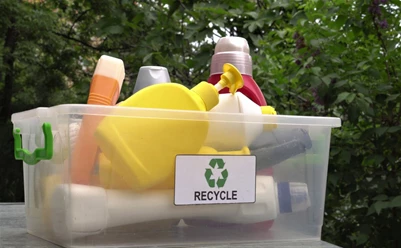 A storage tub with a Recycle sticker full of plastic bottles