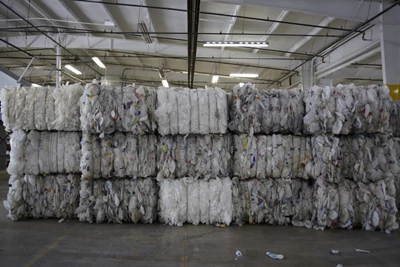 Bundles of flattened plastic products stacked on one another ready to be processed in a recycling center in India