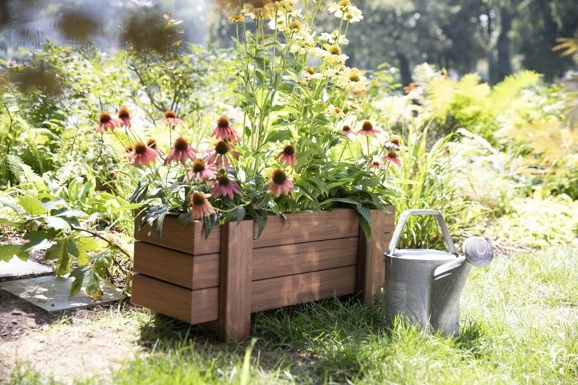 Flowers in a handmade planter box with a gardening water can next to the box.