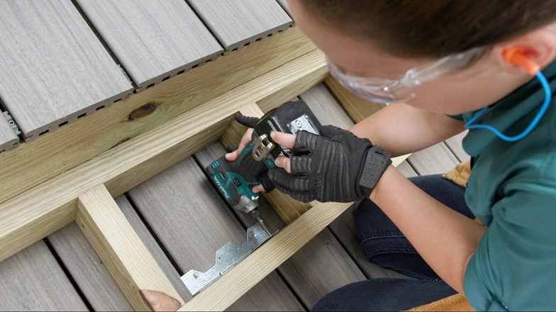 Person with a electric drill in their hand screwing in a bracket