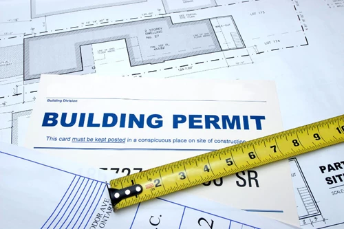 Shows stacks of paper, building permits, and blueprints.