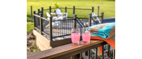 Drink railing installed on a brown deck holding two cocktails